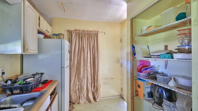 kitchen with white refrigerator, sink, and a textured ceiling