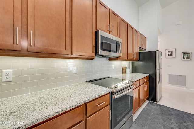 112 Chelsea Place Ave, Ormond Beach, FL 32174 - kitchen with appliances with stainless steel finishes, tasteful backsplash, light stone counters, and brown cabinetry