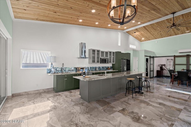 kitchen featuring wooden ceiling, green cabinets, wall chimney range hood, a barn door, and appliances with stainless steel finishes