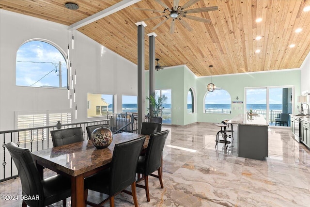 dining space with ceiling fan, a water view, wood ceiling, and high vaulted ceiling