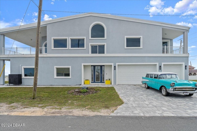 view of front of home featuring a balcony, a garage, and a front lawn