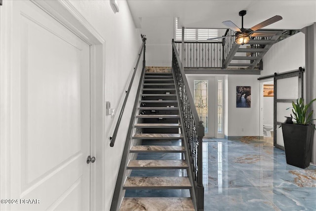 staircase featuring a barn door and ceiling fan