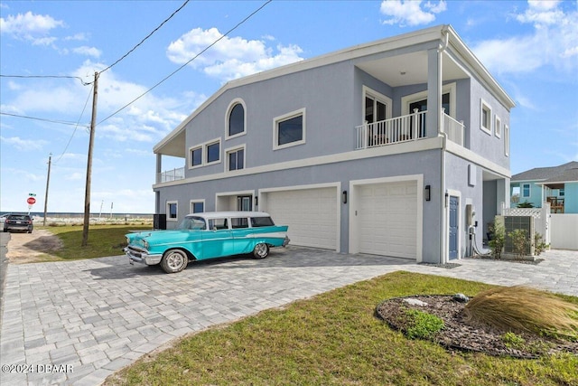 view of front of house featuring a balcony, a front lawn, and a garage