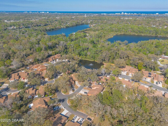 drone / aerial view featuring a forest view, a water view, and a residential view