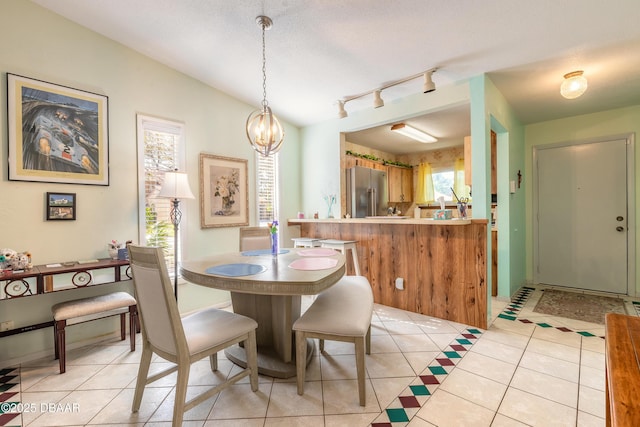 dining space with lofted ceiling, light tile patterned flooring, and a chandelier