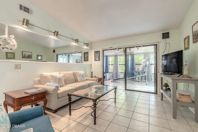 living area featuring light tile patterned flooring, visible vents, and lofted ceiling