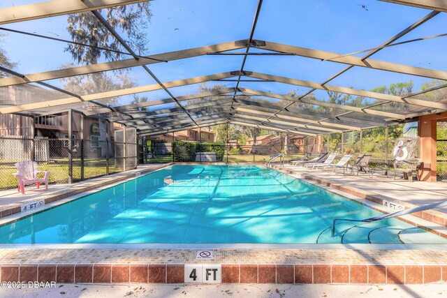 community pool featuring glass enclosure, a patio area, and fence