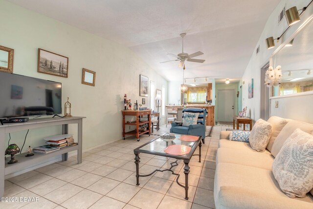 living room with vaulted ceiling, light tile patterned flooring, baseboards, and ceiling fan