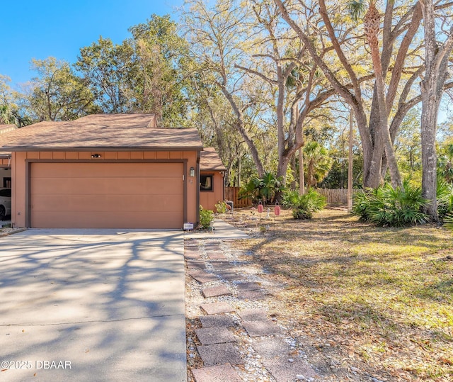 exterior space featuring board and batten siding, concrete driveway, a garage, and fence