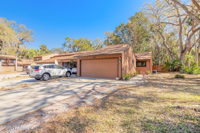 exterior space with an attached garage, board and batten siding, driveway, and fence