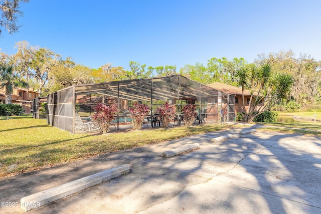 back of house featuring glass enclosure and a yard