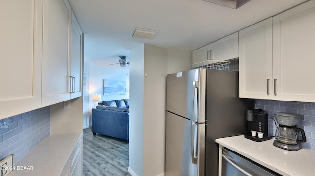 kitchen featuring light hardwood / wood-style floors, white cabinetry, backsplash, and stainless steel appliances