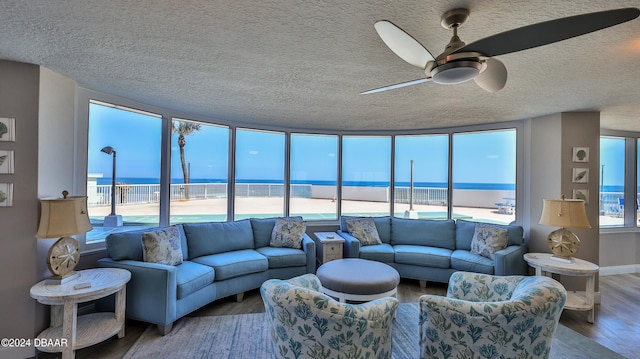 living room featuring ceiling fan, hardwood / wood-style floors, a water view, and a beach view