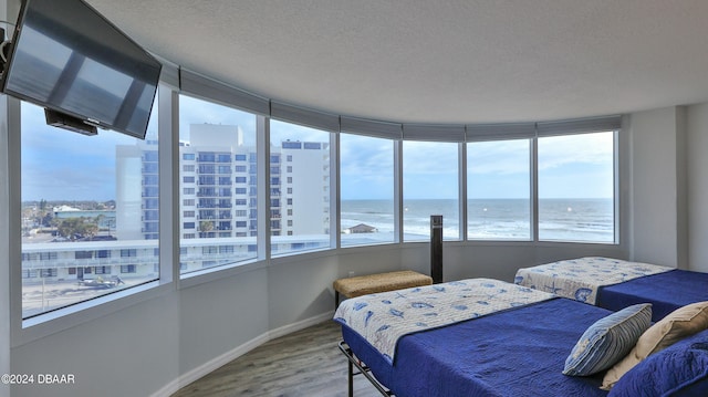 bedroom with a water view, a textured ceiling, and hardwood / wood-style flooring