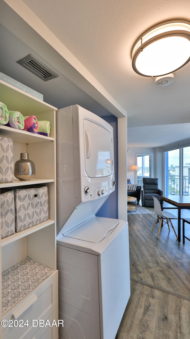 washroom with hardwood / wood-style floors, a textured ceiling, and stacked washer / dryer