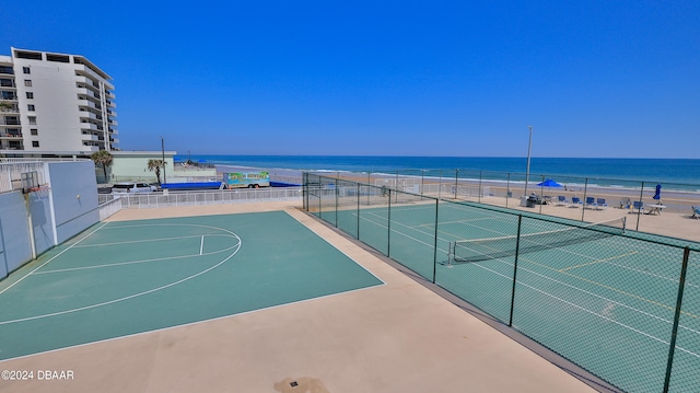 exterior space with basketball hoop, a water view, and a beach view