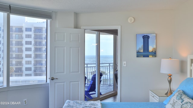 bedroom with multiple windows, a water view, wood-type flooring, and access to exterior