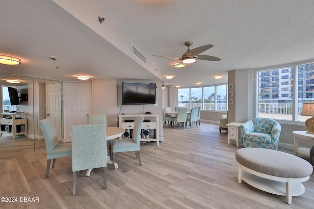 dining area with ceiling fan, light hardwood / wood-style floors, and a textured ceiling