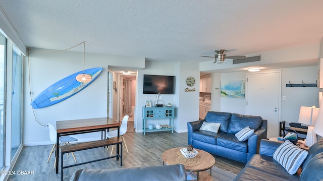 living room featuring ceiling fan, wood-type flooring, and a textured ceiling