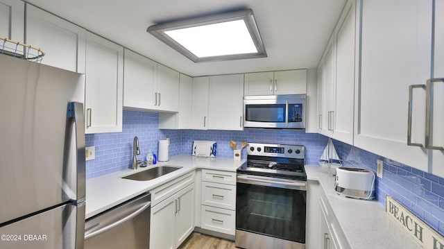 kitchen with decorative backsplash, white cabinetry, sink, and appliances with stainless steel finishes