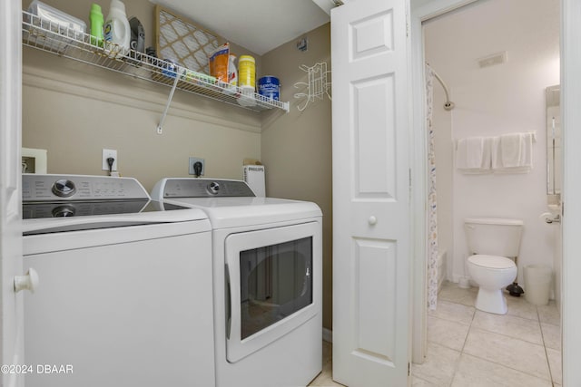 clothes washing area with light tile patterned flooring and independent washer and dryer