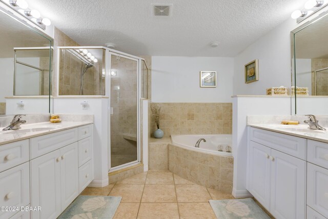 5300 S Atlantic Ave Unit 15-403, New Smyrna Beach, FL 32169 - full bathroom featuring a stall shower, two vanities, tile patterned flooring, a garden tub, and a textured ceiling