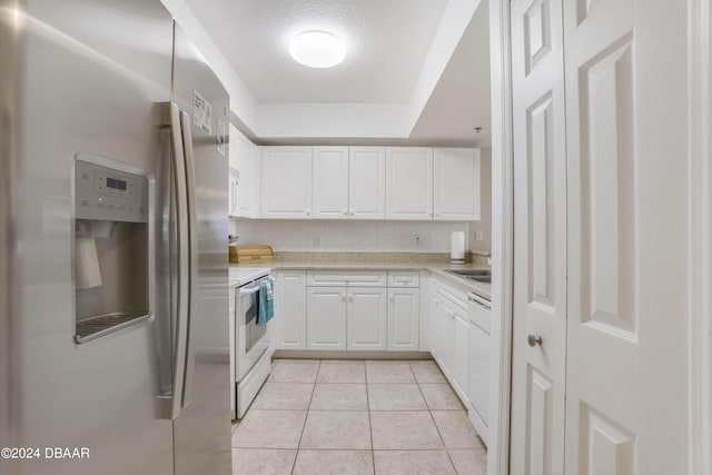 kitchen with white cabinets, a textured ceiling, light tile patterned floors, sink, and white appliances