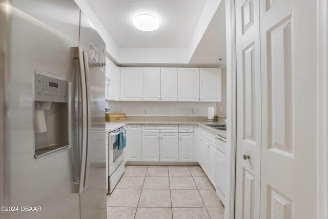 5300 S Atlantic Ave Unit 15-403, New Smyrna Beach, FL 32169 - kitchen featuring white appliances, light countertops, white cabinetry, light tile patterned flooring, and tasteful backsplash