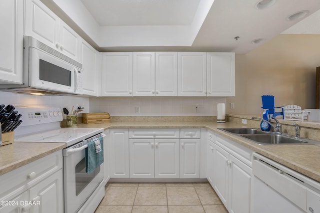 kitchen with white cabinets, decorative backsplash, sink, light tile patterned floors, and white appliances