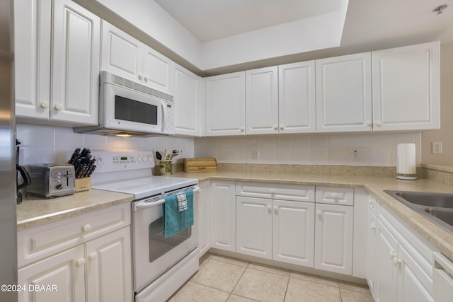 kitchen with white cabinets, light tile patterned floors, and white appliances