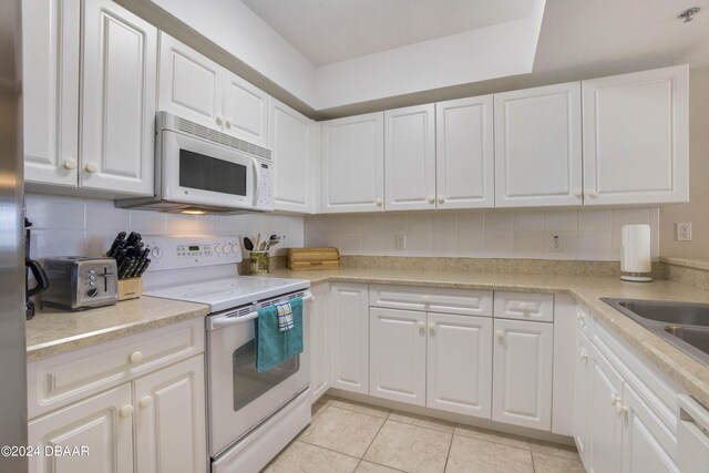 5300 S Atlantic Ave Unit 15-403, New Smyrna Beach, FL 32169 - kitchen featuring white appliances, white cabinets, light tile patterned floors, and tasteful backsplash