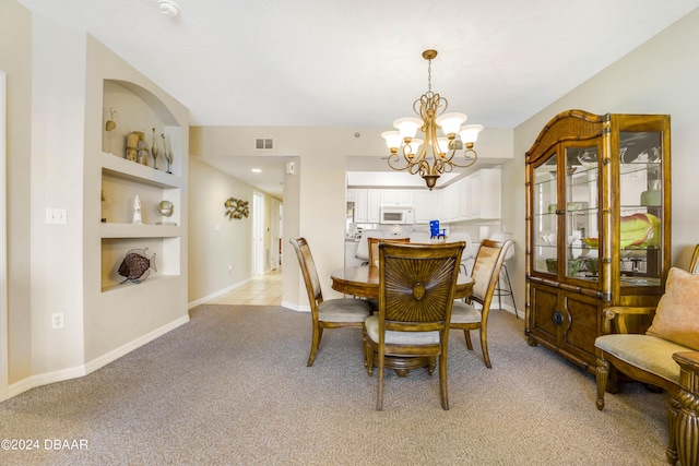 dining room featuring built in shelves, light colored carpet, and a notable chandelier