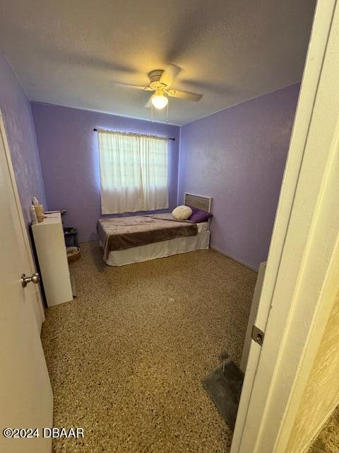 bedroom with ceiling fan and a textured ceiling