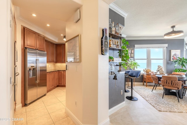 2515 S Atlantic Ave Unit 703, Daytona Beach, FL 32118 - kitchen with built in refrigerator, ornamental molding, brown cabinetry, light tile patterned floors, and backsplash