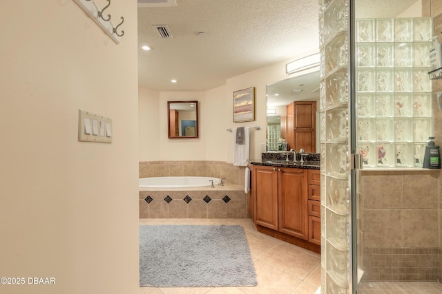 2515 S Atlantic Ave Unit 703, Daytona Beach, FL 32118 - full bathroom featuring vanity, tile patterned flooring, a garden tub, a textured ceiling, and a shower stall