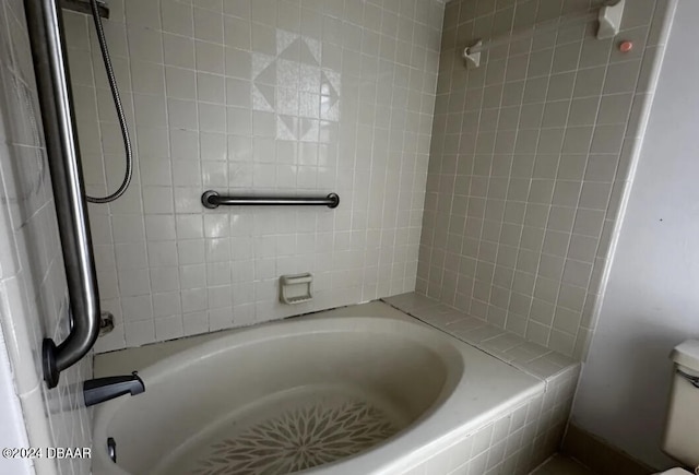 bathroom featuring toilet and tiled shower / bath combo