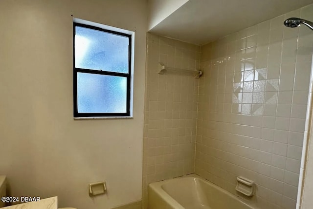 bathroom with toilet and tiled shower / bath combo