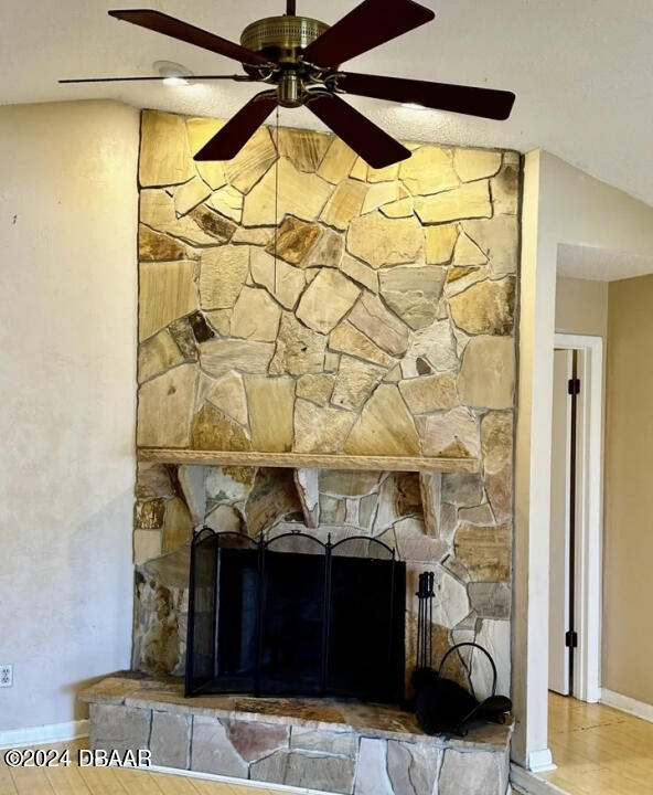 room details with a stone fireplace, hardwood / wood-style flooring, and ceiling fan