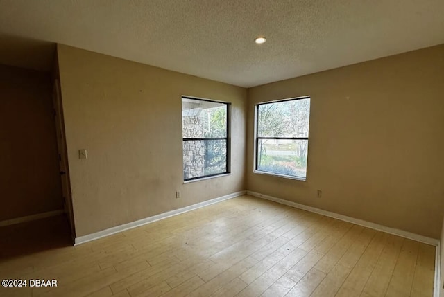 unfurnished room featuring light hardwood / wood-style flooring and a textured ceiling