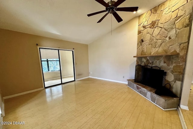 unfurnished living room with ceiling fan, a stone fireplace, light wood-type flooring, and vaulted ceiling