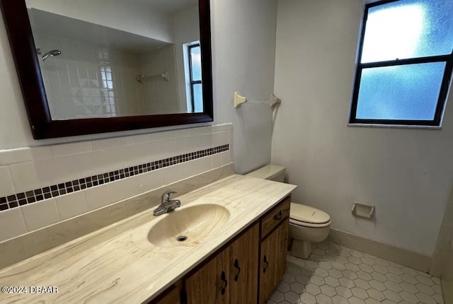 bathroom featuring toilet, vanity, a healthy amount of sunlight, and tile patterned floors