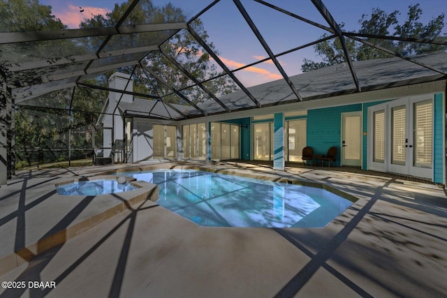 pool at dusk featuring a patio, a lanai, and french doors