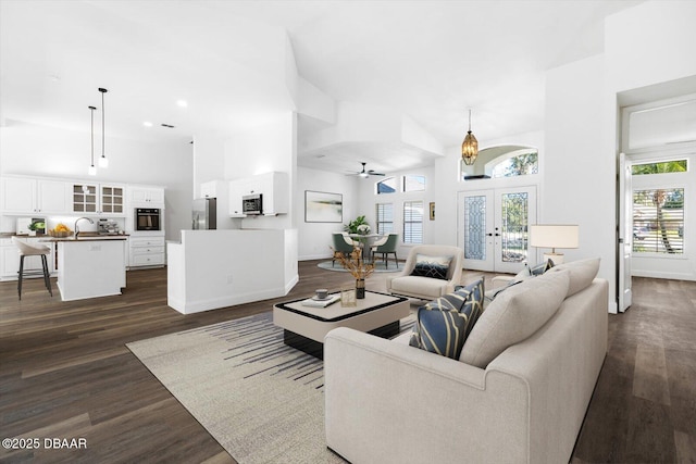 living room featuring sink, ceiling fan, a high ceiling, dark hardwood / wood-style flooring, and french doors