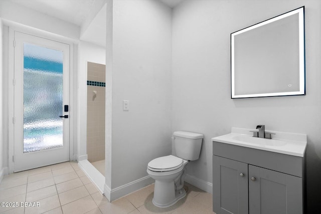 bathroom with a tile shower, vanity, tile patterned floors, and toilet