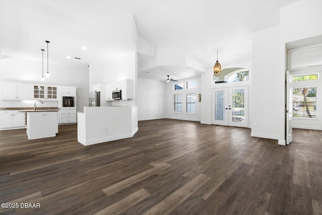 unfurnished living room with plenty of natural light, a towering ceiling, and french doors