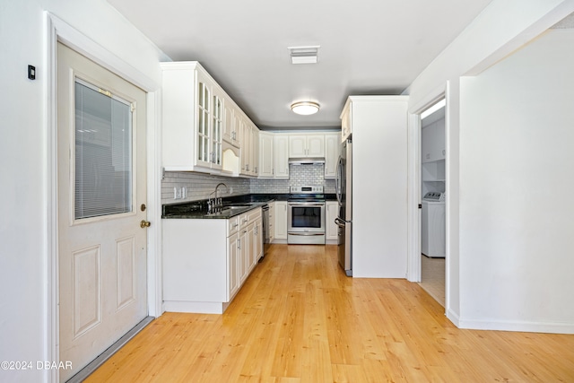 kitchen with washer / dryer, white cabinetry, stainless steel appliances, tasteful backsplash, and sink