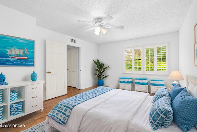 bedroom featuring ceiling fan, wood-type flooring, and a textured ceiling