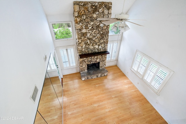 living room with a healthy amount of sunlight, wood-type flooring, a fireplace, and a high ceiling