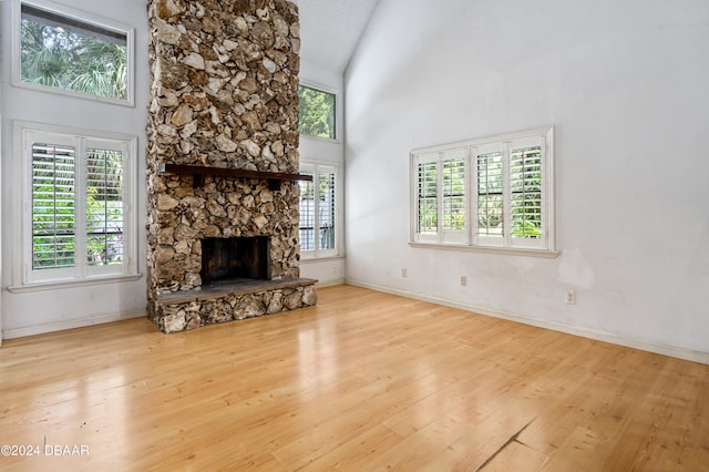 unfurnished living room featuring high vaulted ceiling, a fireplace, and light hardwood / wood-style floors