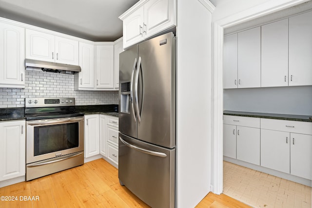 kitchen with decorative backsplash, white cabinets, appliances with stainless steel finishes, and light hardwood / wood-style floors